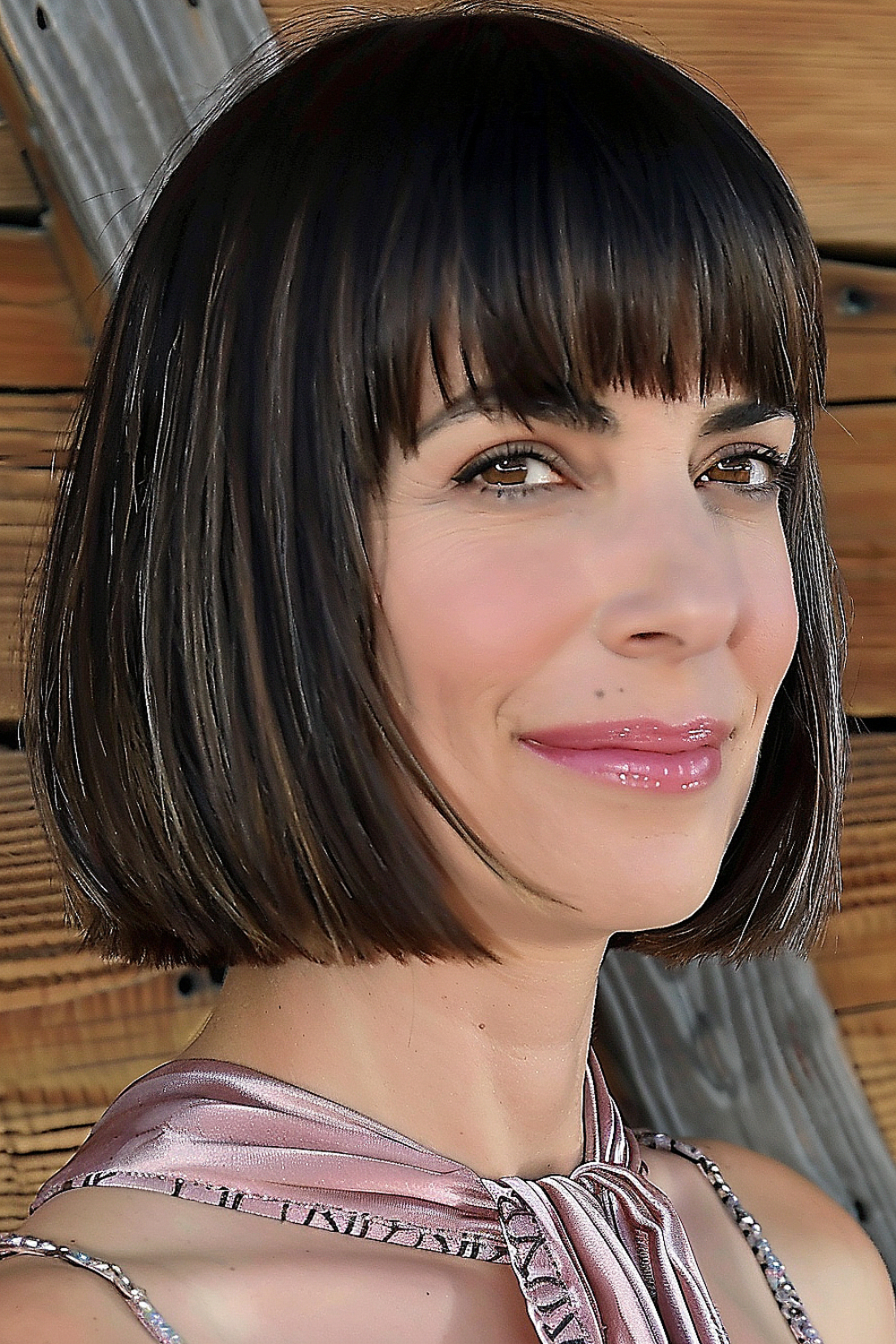 Woman with a sleek, dark brown blunt bob and straight-across bangs