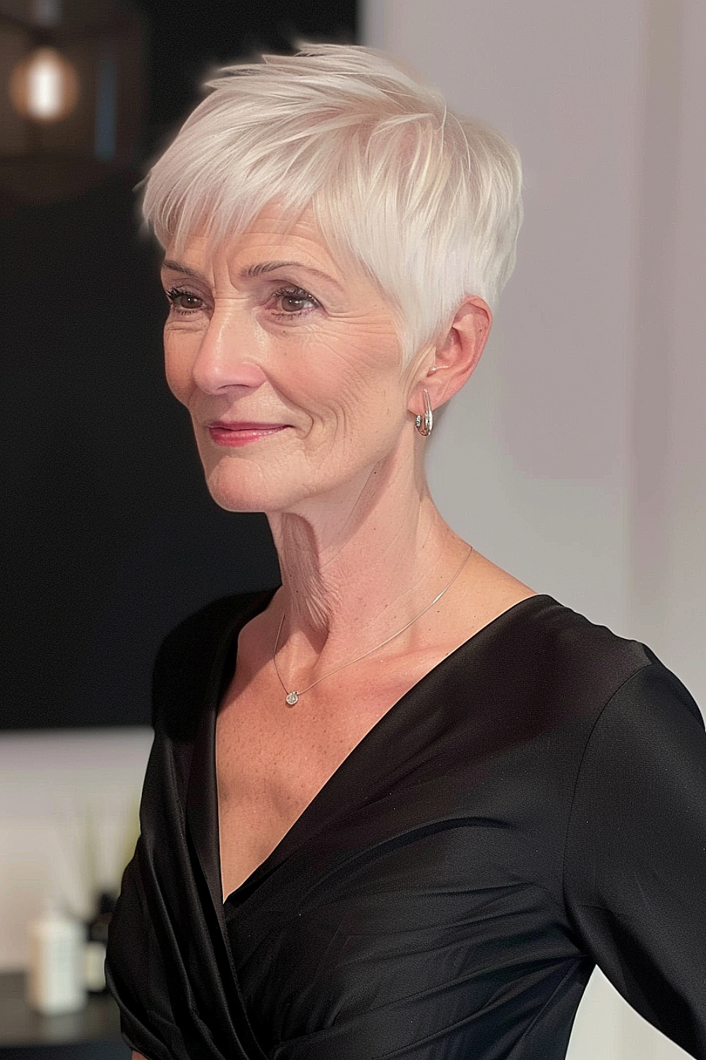 Elderly woman with a short platinum pixie haircut, featuring textured layers and side-swept bangs.