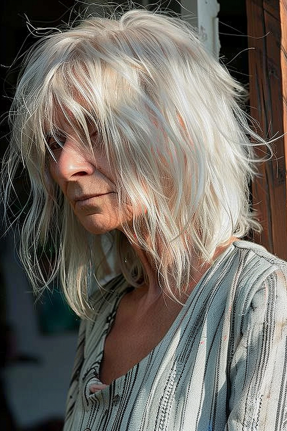 A woman with a chic undone shag hairstyle in platinum blonde, featuring long layers and wispy ends.