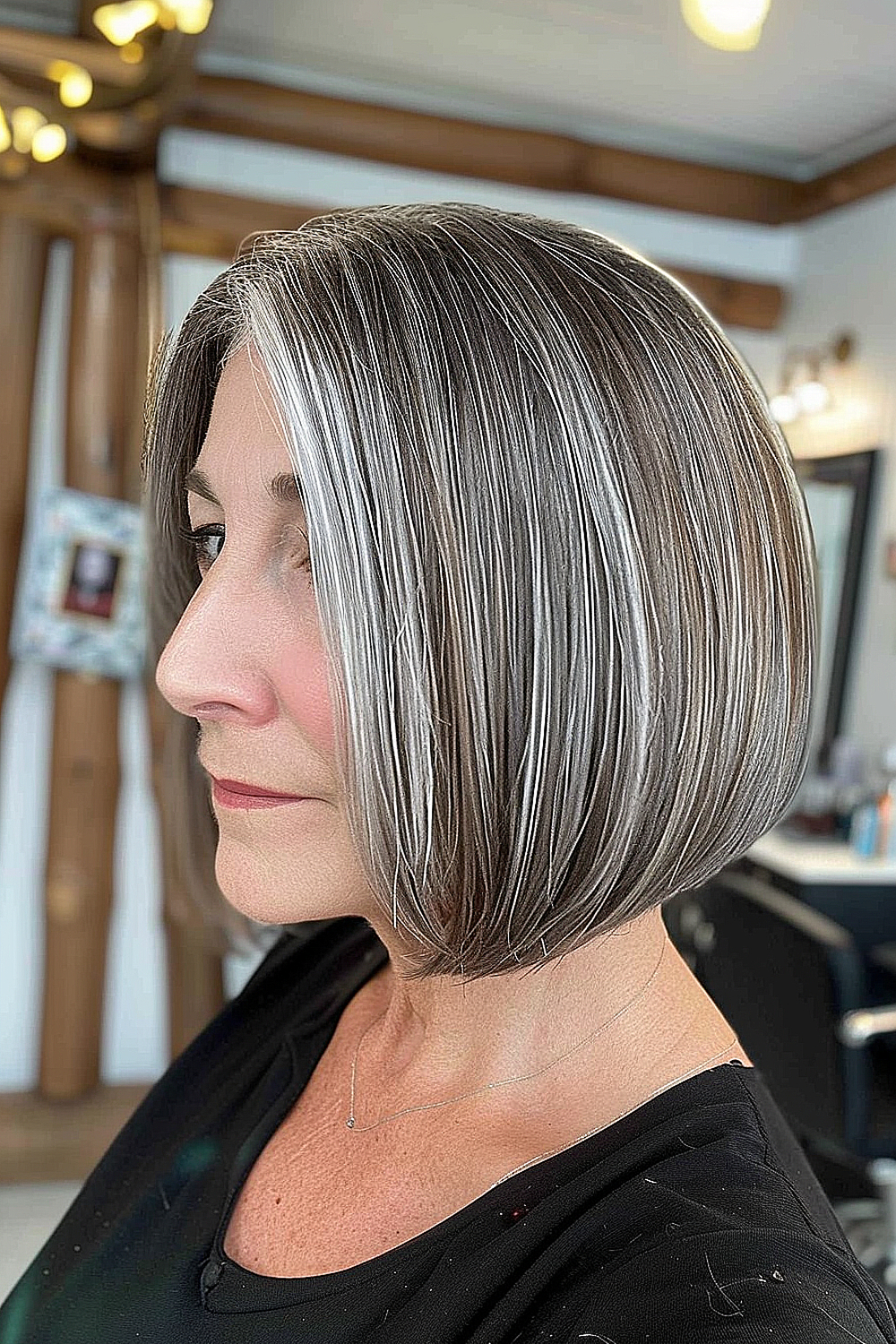 Side profile of a woman with a classic A-line bob featuring sleek silver highlights