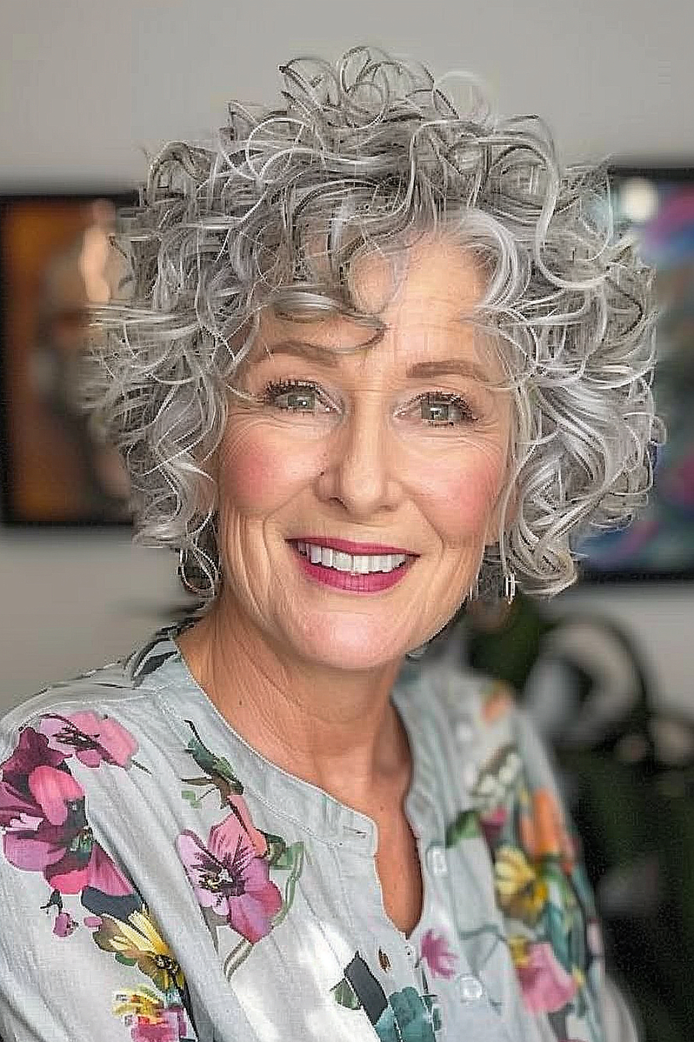 Woman over 70 with a curly bixie haircut enhanced with lowlights, showcasing voluminous curls