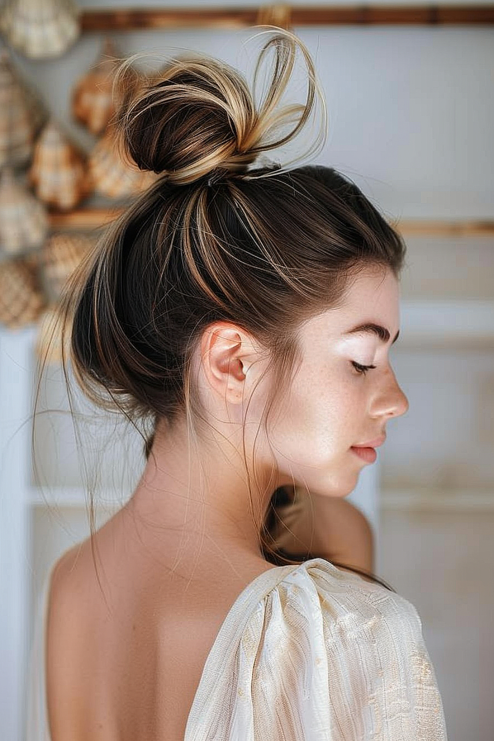 Woman with a high bun featuring subtle streaks