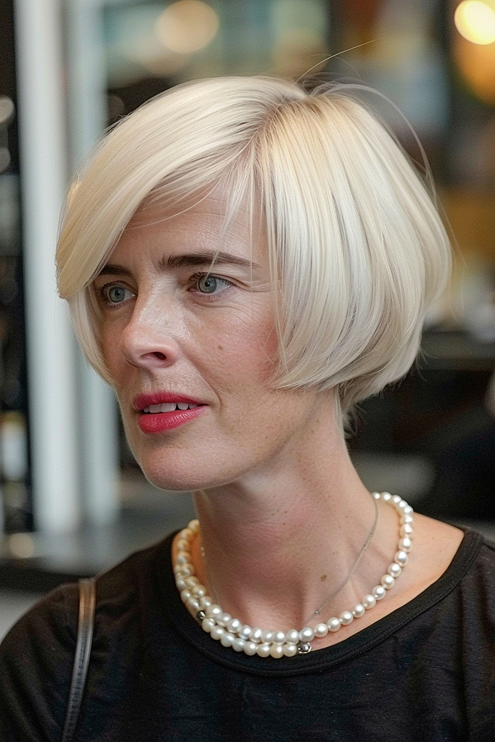 A woman with a jaw-length bob in a shiny platinum blonde finish, styled sleekly to enhance its elegant silhouette