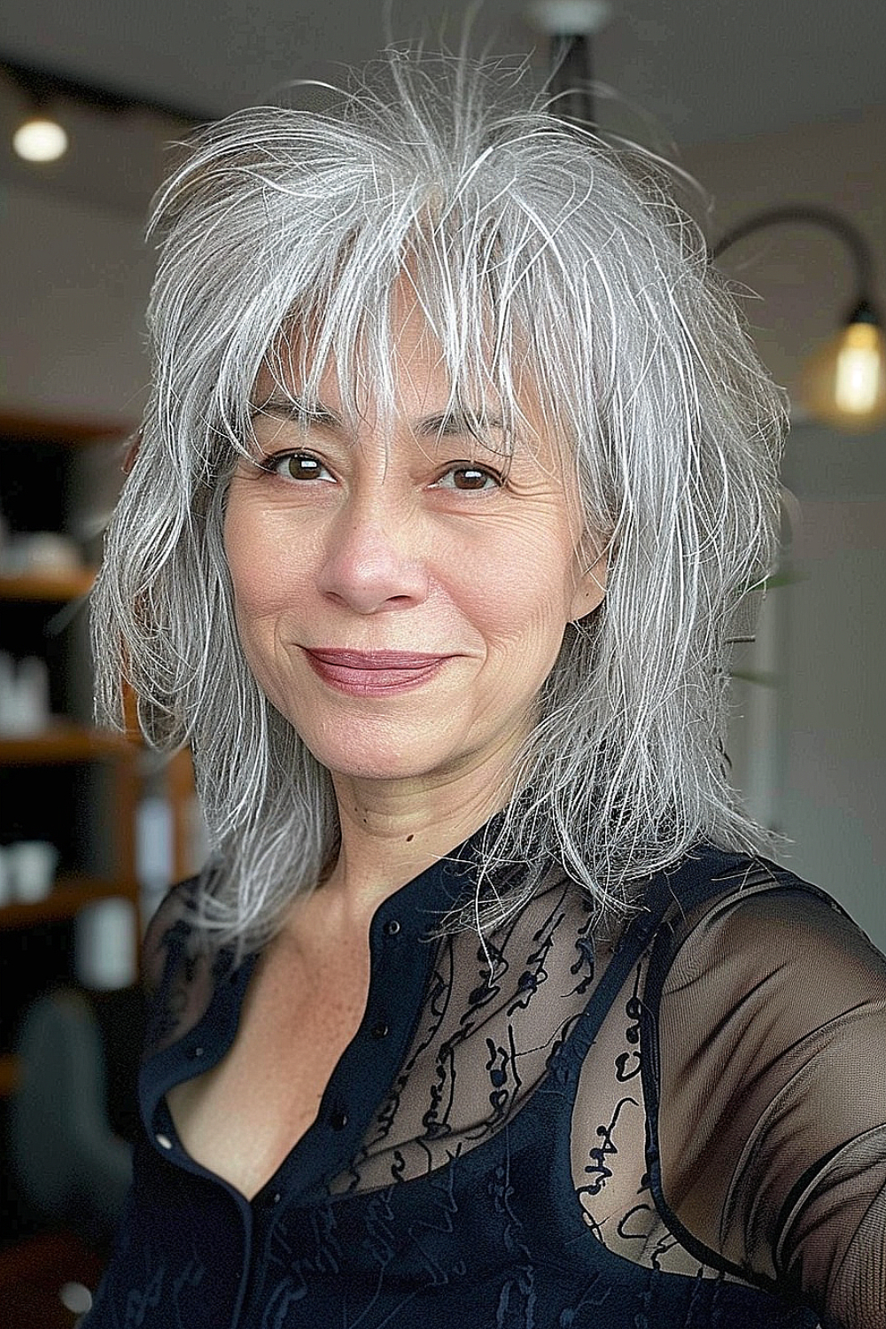 A woman with a layered silver shag hairstyle, showing off voluminous, tousled layers and natural grey tones.