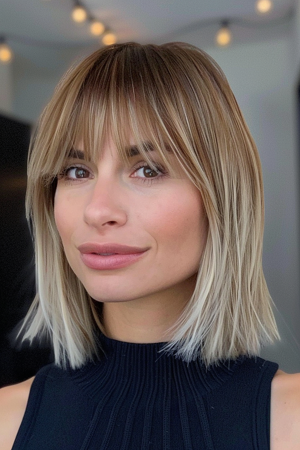 Woman with a long bob and tapered bangs, featuring blonde highlights