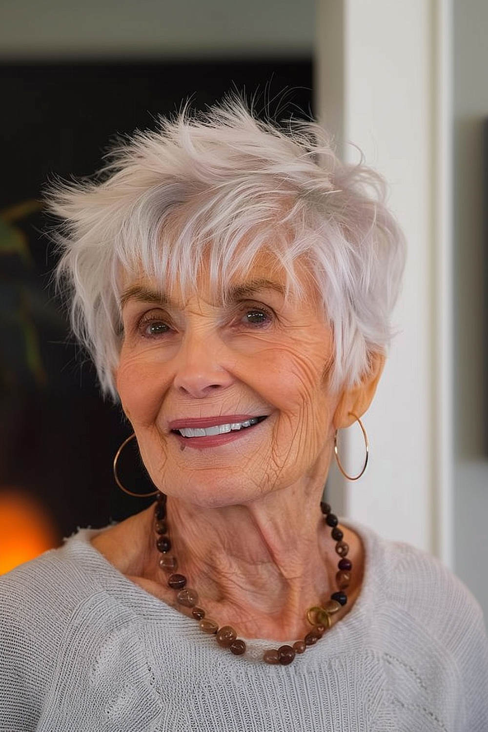 Smiling older woman with a white-silver modern pixie cut featuring a textured top.