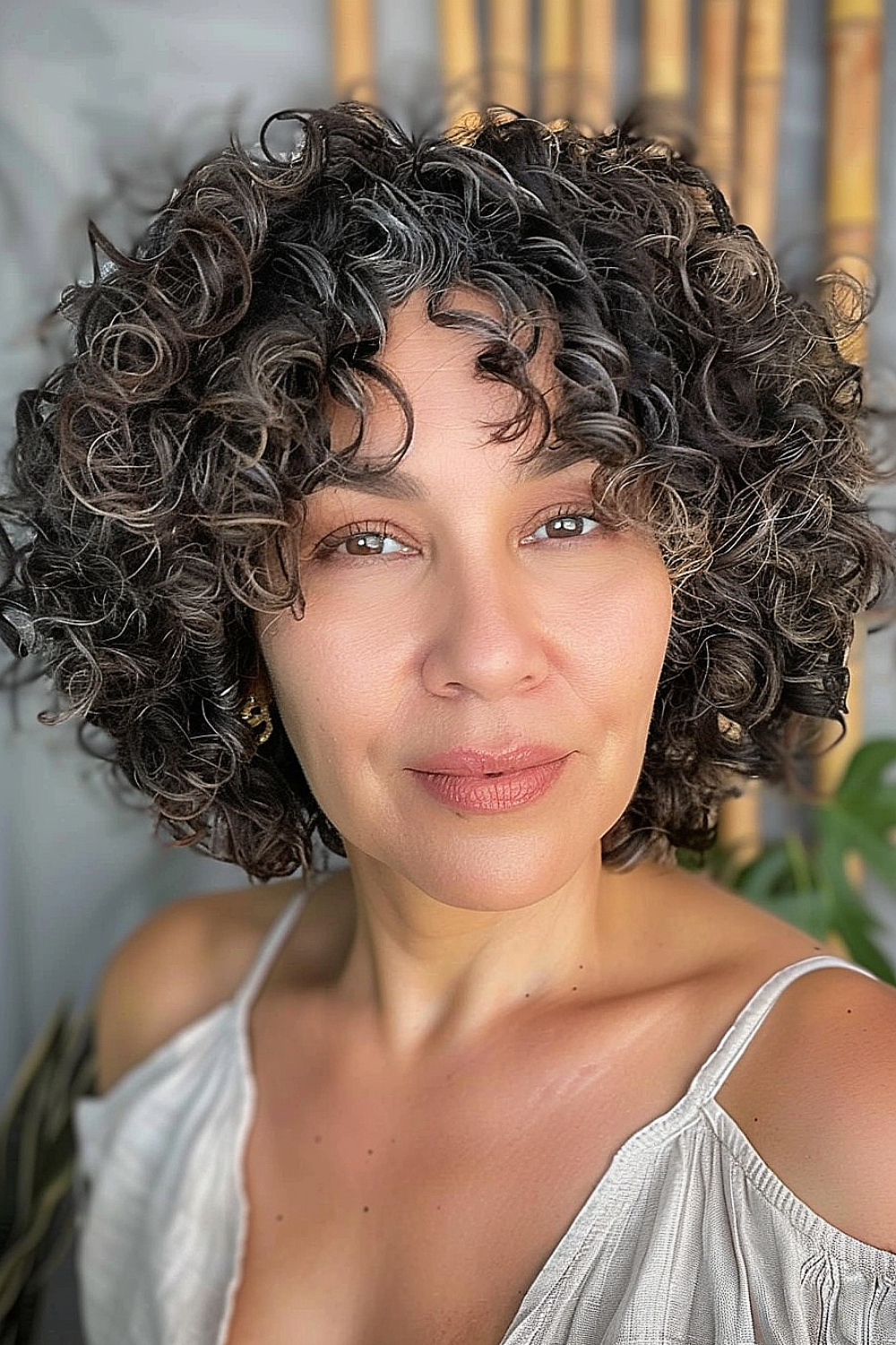 A woman with a natural curly bob, highlighted subtly to enhance the curls' texture and volume