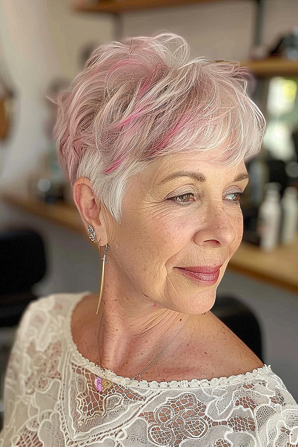 Romantic pixie cut with soft pink highlights on a woman over 50