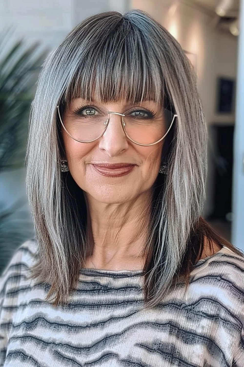 Woman with a sophisticated straight shoulder-length cut and full bangs, wearing glasses