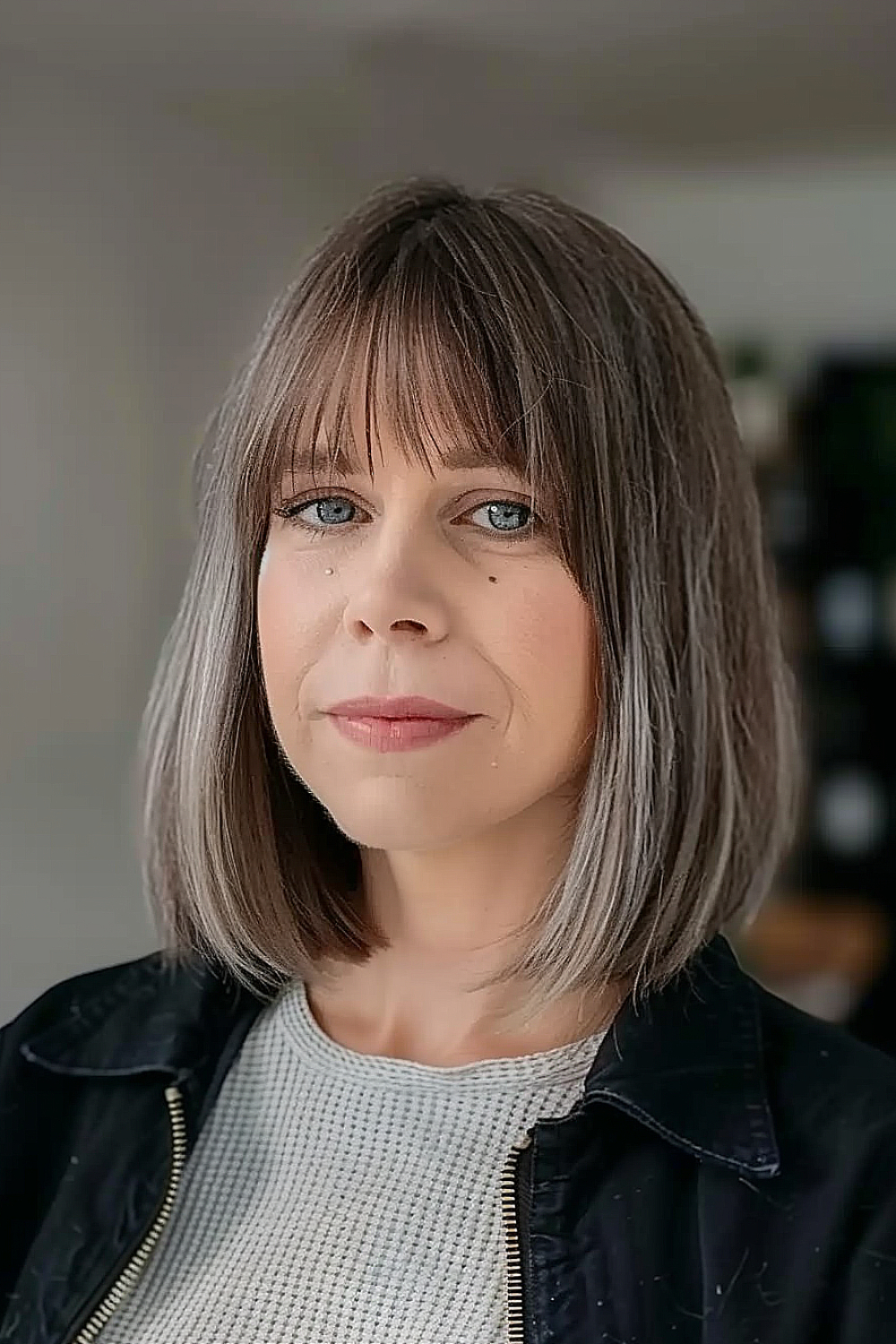 Woman with a straight lob and peek-a-boo bangs, featuring a dark to light ombre effect