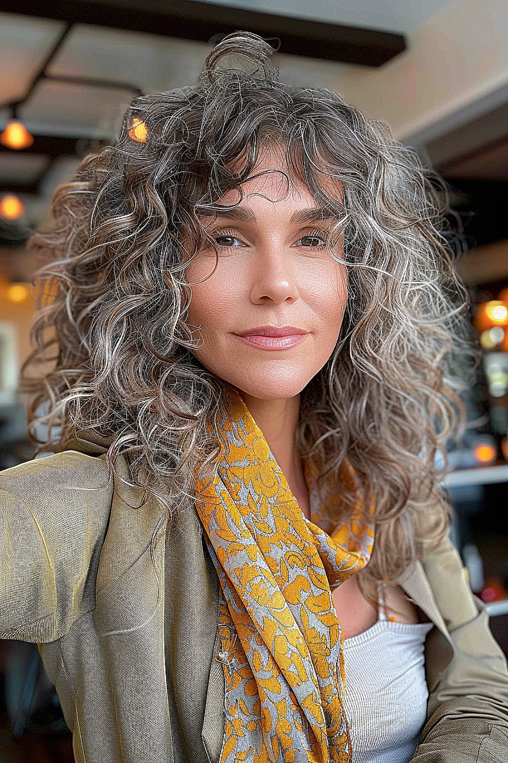 Woman with textured curly shag hairstyle featuring gray highlights