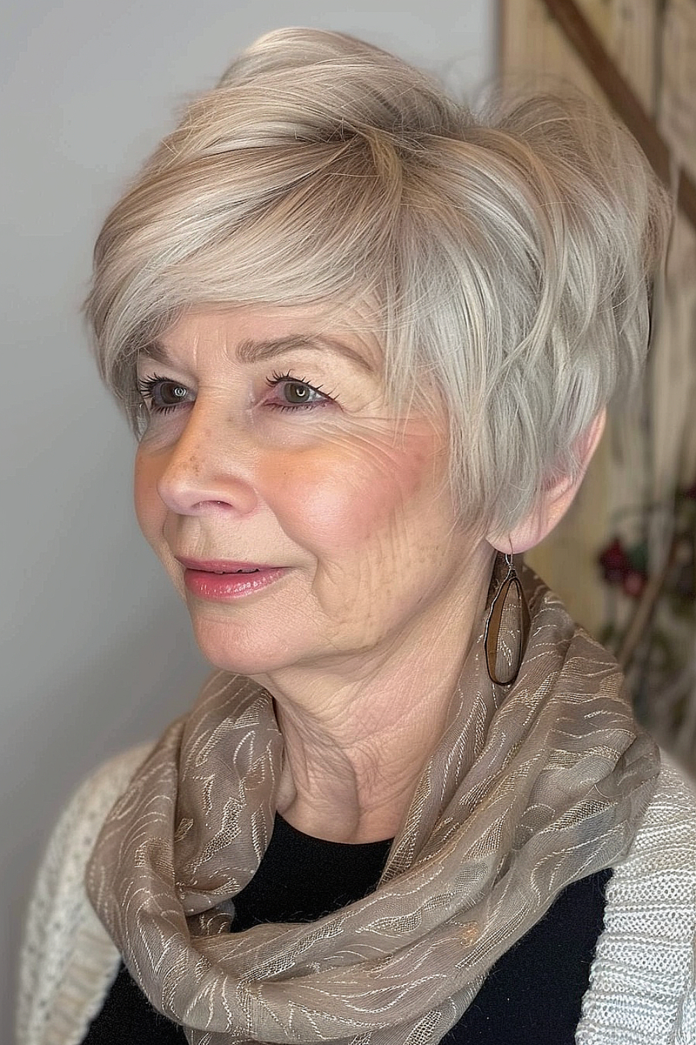 Senior woman with a textured pixie cut featuring long, sweeping bangs in a soft silver color