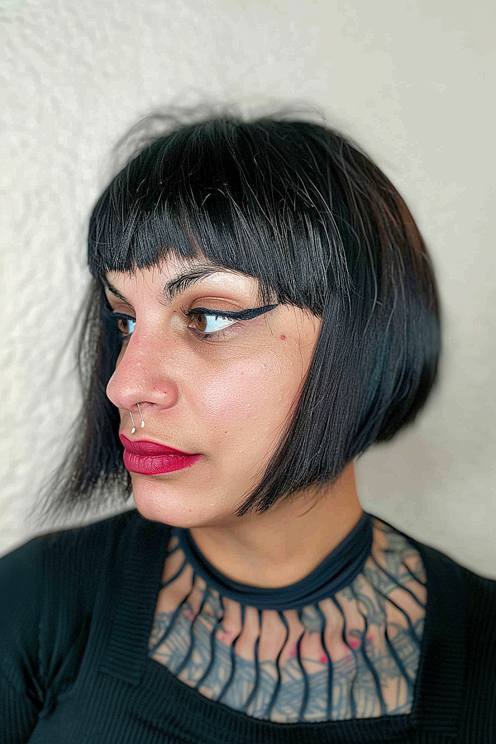 Woman with a jet-black V-shaped bob and sharp angled bangs