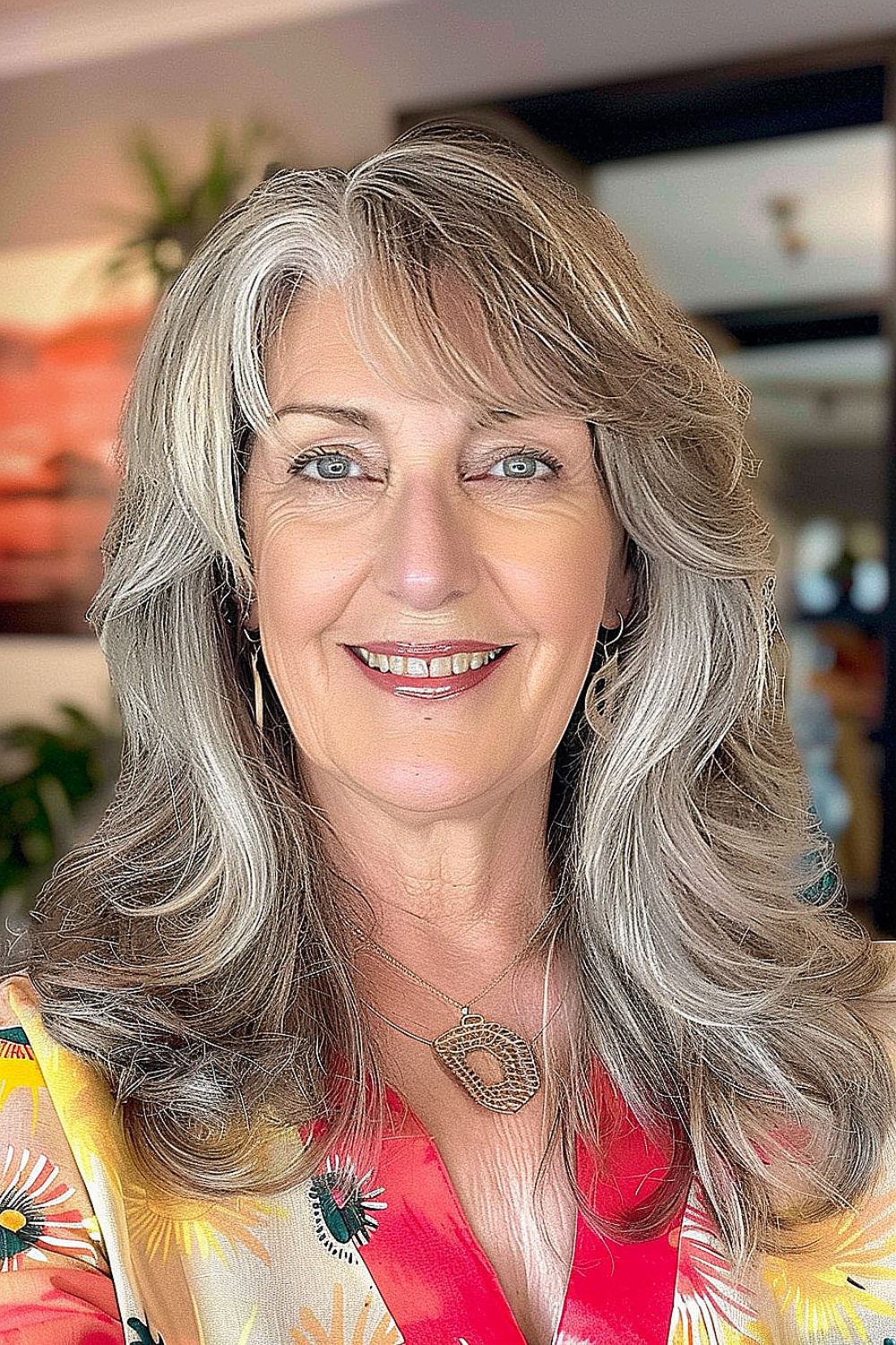 Woman over 60 with voluminous medium-length silver hair and darker roots